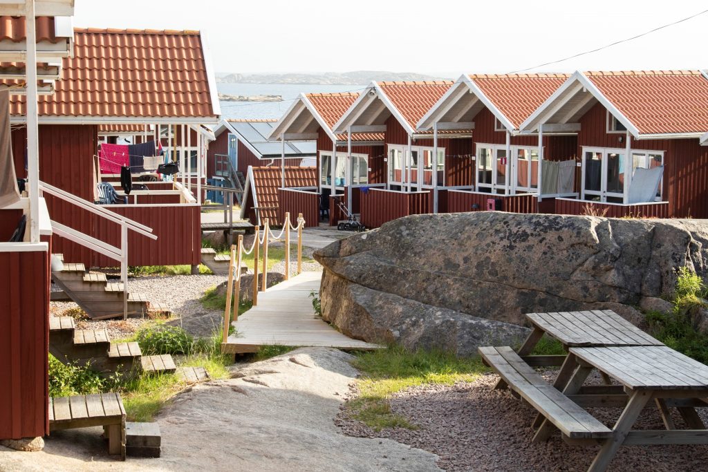 Flertalet röda stugor på Ramsvik Stugby & Camping nära Smögen på Västkusten. En solig sommardag.